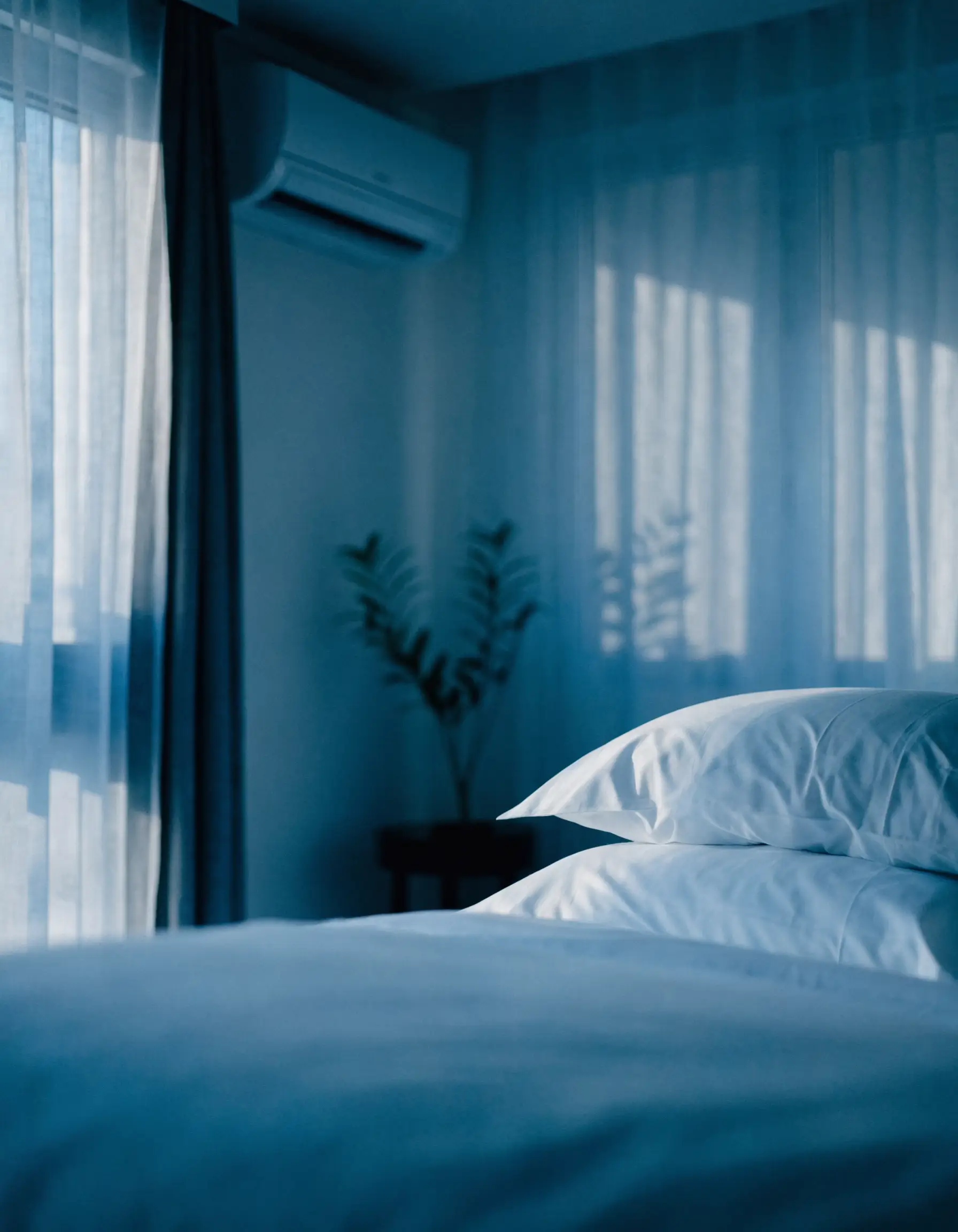 A calm, cool bedroom in soft morning light with a slim wall-mounted unit