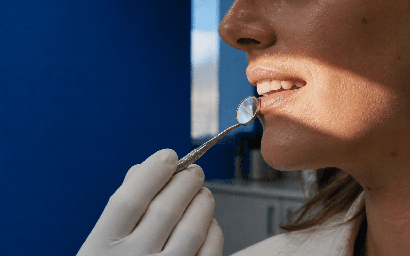 Patient smiling naturally while a clinician holds a dental mirror